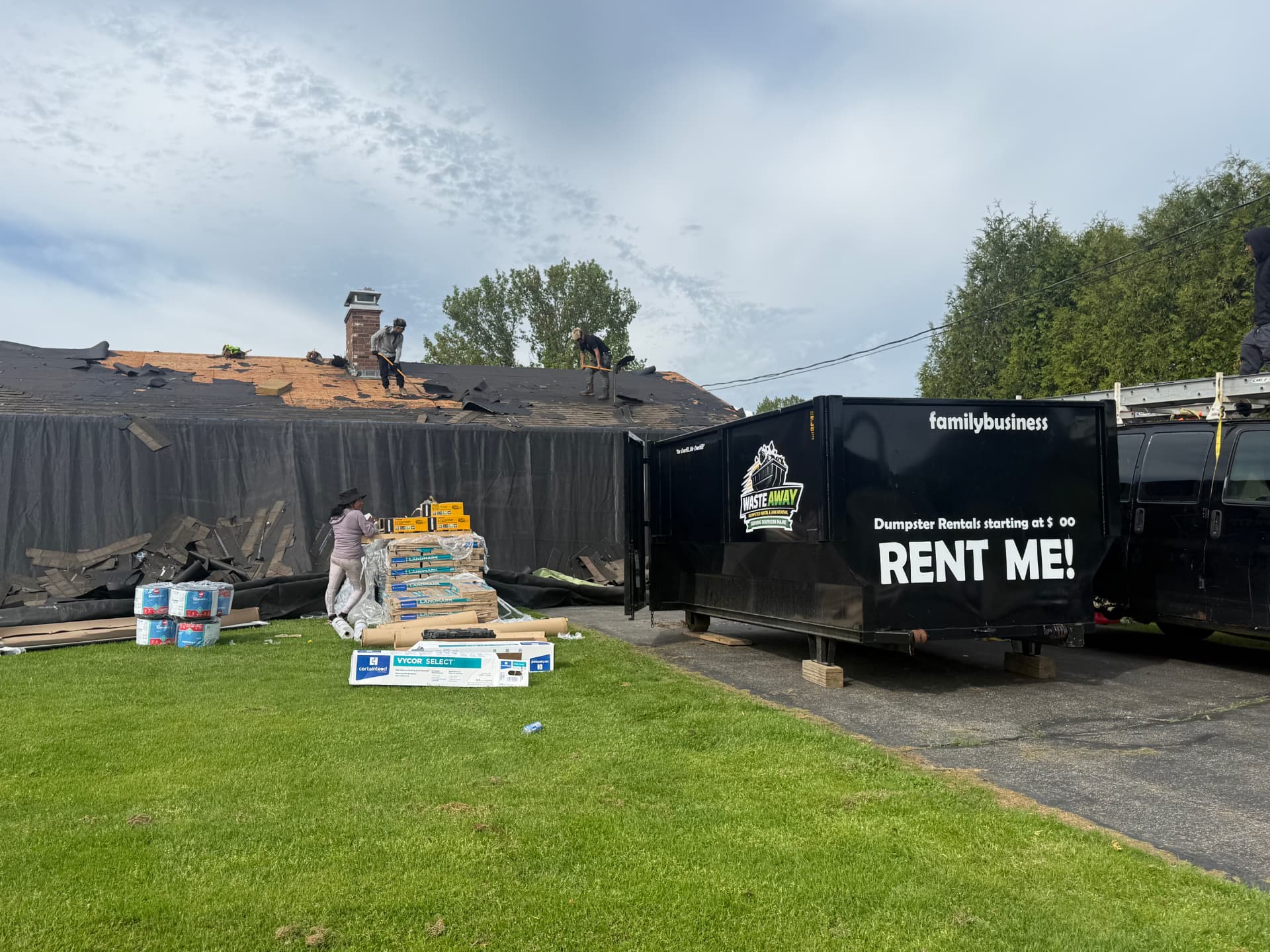 Waste Away black 16-yard roll-off dumpster parked on a Southern Maine driveway during a residential roofing tear-off